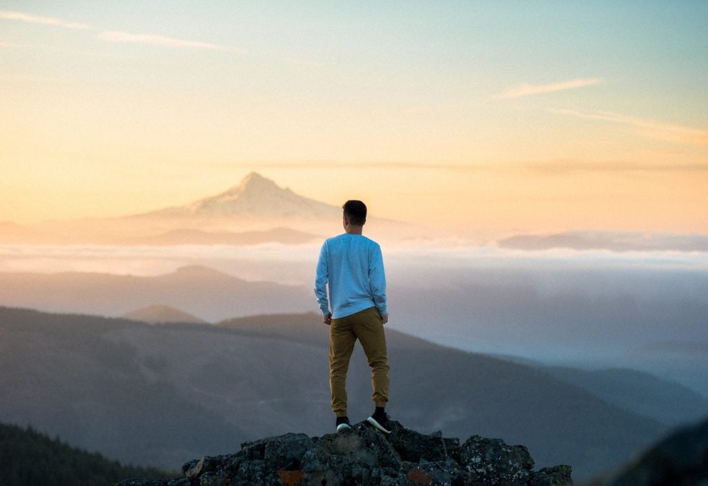 Man Looking over Mountains at peak of mountain